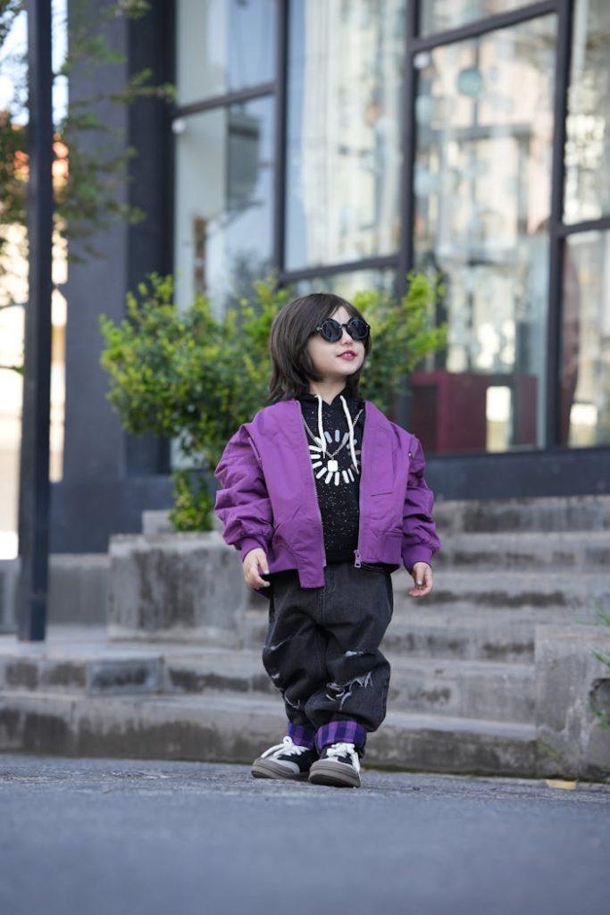 Stylish Child in Purple Jacket and Sunglasses Outdoors